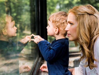 Side View of Toddler and Mother In Front of Safety Glass