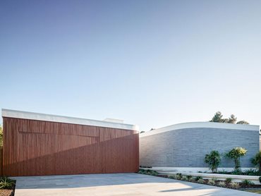 The vertical timber look aluminium battens effectively disguise the garage door by effortlessly integrating with the building’s sculptural element