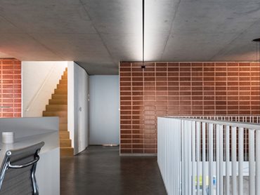 Internally, the unglazed terracotta-coloured clay responds to the refined grey concrete walls and the textured white painted brick walls
