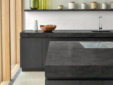 Interior of modern kitchen with dark gray solid bench surface