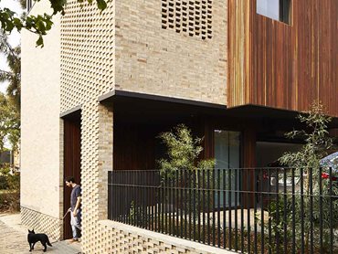 The natural earthy hues of the timber and brickwork are stitched together by a handful of darker building elements, balustrade rails and external louvres