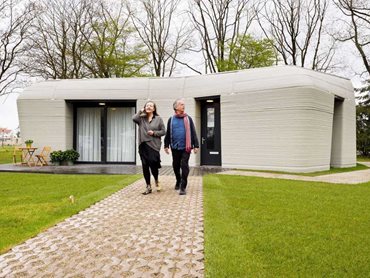 Elize Lutz and Harrie Dekkers in front of their new 3D-printed concrete home from Project Milestone