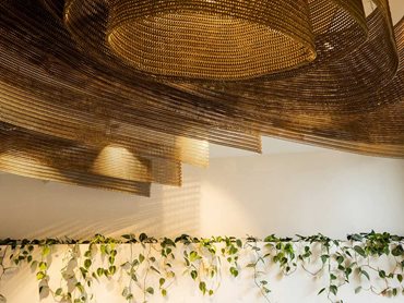 The ceiling feature replicates a honeycomb's geometric patterns, further enhanced by the bronze colour Kaynemaile mesh 