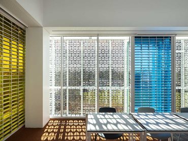 A bespoke perforated solar screen in pre-patinated copper veils the building to control light and solar penetration