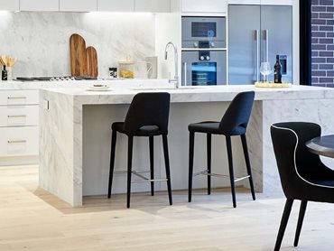 The engineered timber flooring complements other design elements such as natural stone island benchtops
