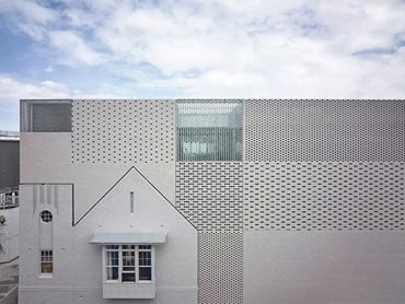 The striking variegated facade of clear Poesia glass bricks and solid light clay bricks