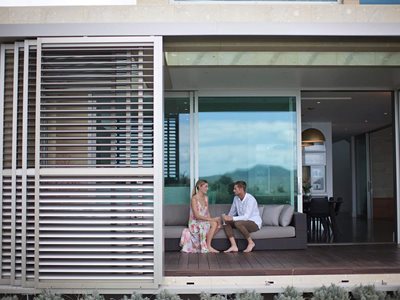 LouvreTec White Shutters on House Exterior With Couple Sitting on Couch