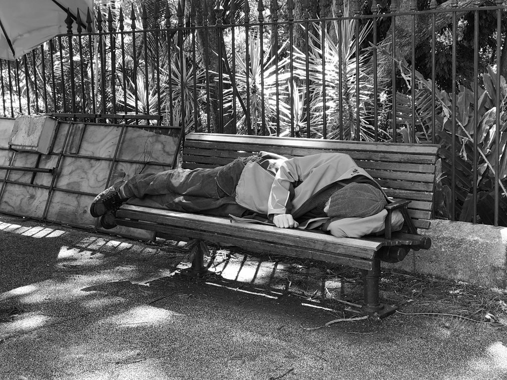 A homeless man sleeps on a bench. Image: Flickr

