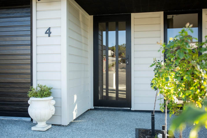 Rusticated weatherboards feature white house front door